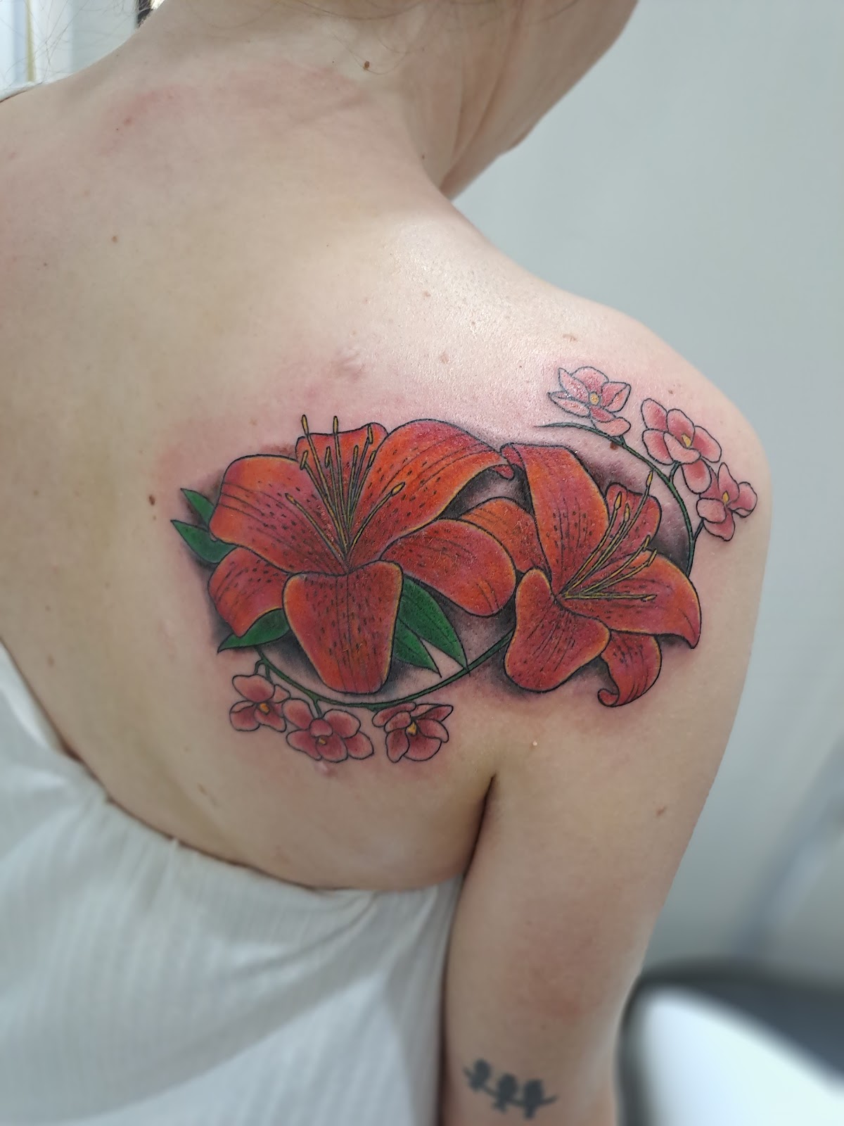 Tatuaje floral a color en hombro, trabajo real de Devil Twin Tattoo Studio